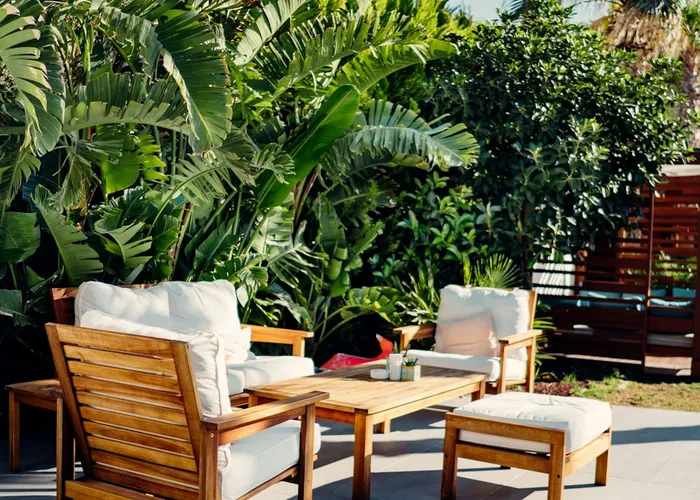 A clean stone patio with wooden outdoor furniture in bright daylight